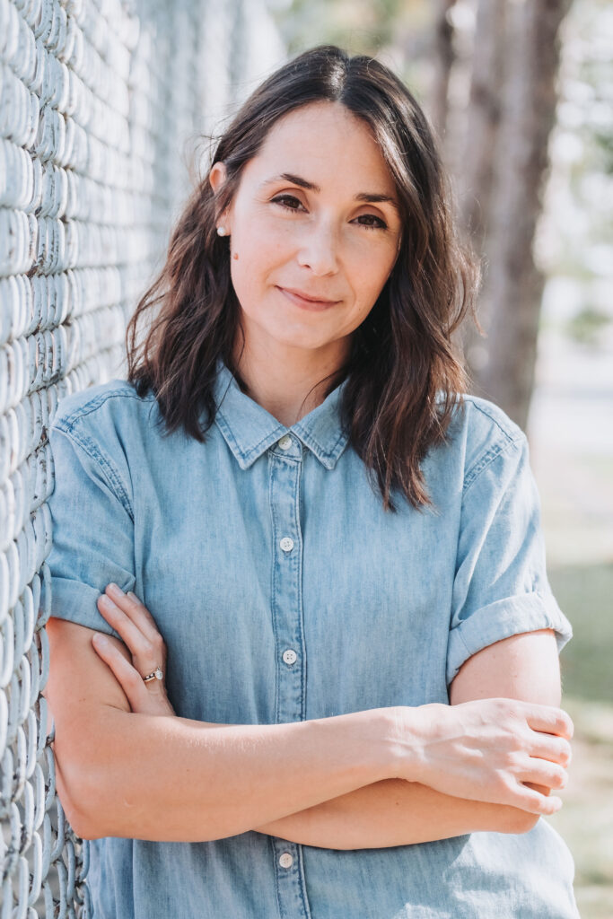 Ardath Whynacht stands against a fence with folded arms.